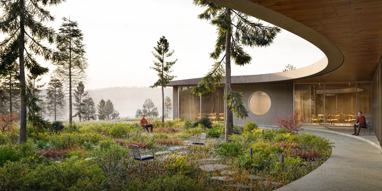 The curved inner courtyard, with its timber canopy and round window, and a dense garden with seats in the foreground.