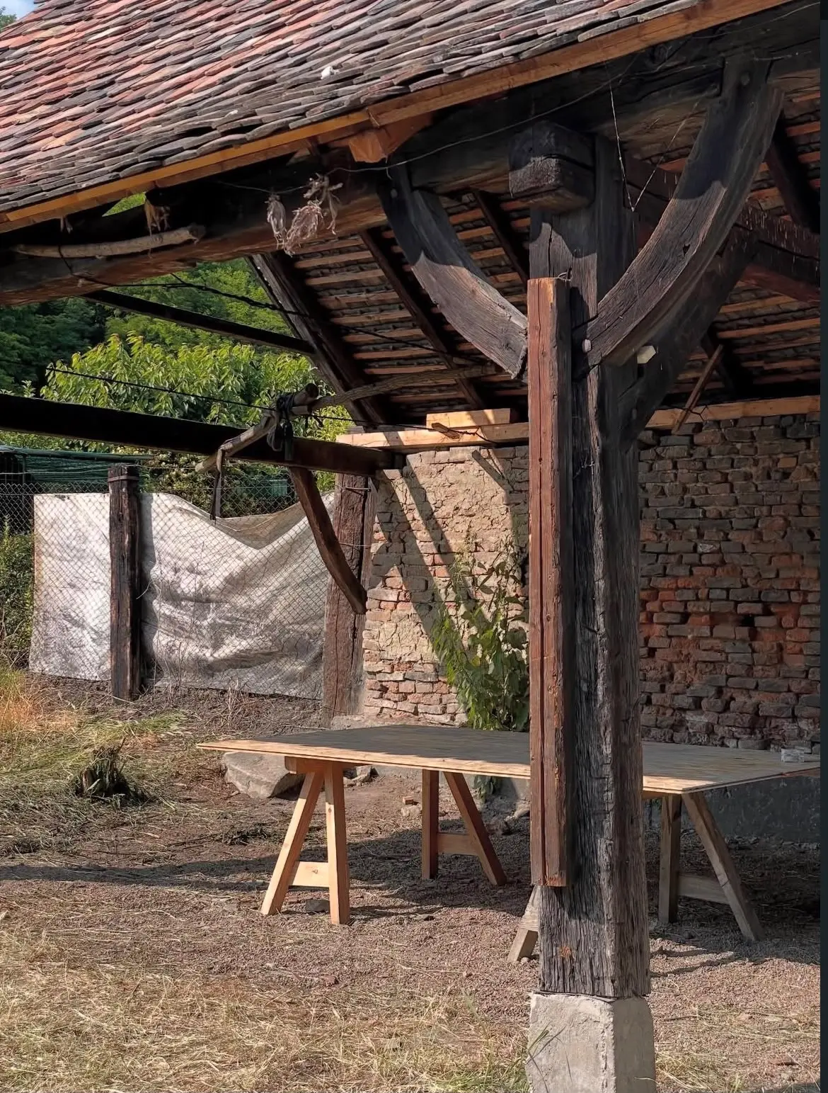 The existing open-fronted shed, with its timber structure, pantile roof and brick rear wall.