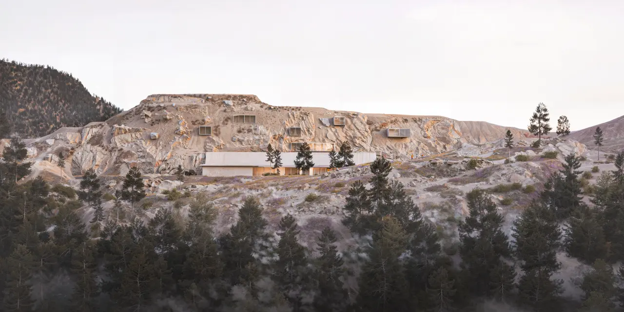 Panoramic view of the quarry, with a long block set into the base of the rock face and openings cut into the stone.